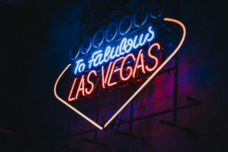 Bright neon sign illuminating a bustling Las Vegas street, capturing the vibrant nightlife atmosphere.