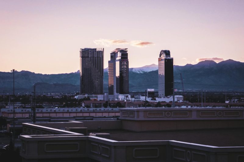Las Vegas skyline illuminated at dusk, framed by mountains in the background.