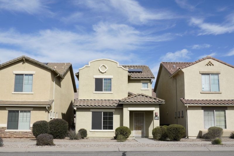 Three suburban houses in Tucson, Arizona, under a clear blue sky.