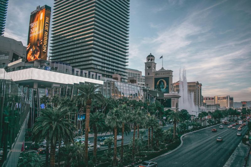 Vibrant Las Vegas skyline with modern buildings and neon lights along a busy boulevard at dusk.