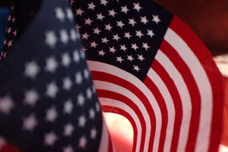 Close-up of a waving American flag featuring vivid stars and stripes against a clear sky.